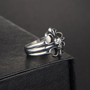 Close-up of vintage titanium steel ring with gothic skull and fleur-de-lis reliefs