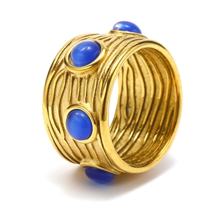 Détail d'une bague large plaquée or avec textures en relief et pierres bleues incrustées