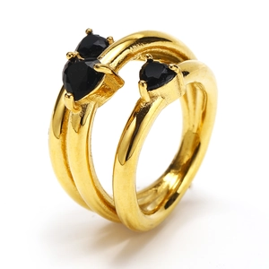 Dettaglio macro di anello dorato a doppio strato con tre zirconi neri a forma di cuore