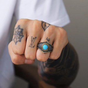 Detalle macro de anillo punk vintage con piedra turquesa redonda y grabado étnico