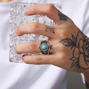 Detalle de anillo punk retro para hombre con piedra turquesa y acabado bicolor dorado