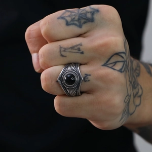 Detalle de anillo punk vintage de acero con gema negra en mano tatuada