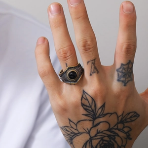Vista detallada de un anillo punk vintage con gema negra en una mano tatuada