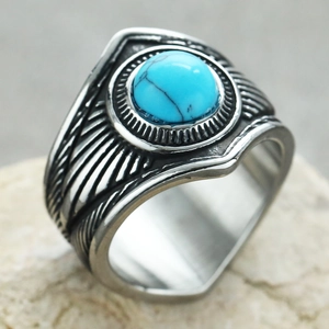 Detalle macro de un anillo punk vintage con piedra turquesa y grabado de plumas