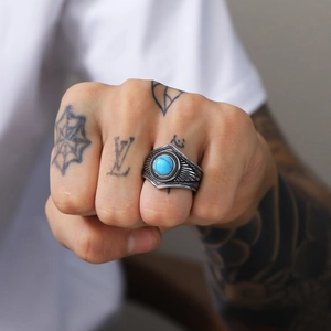 Detalle de anillo punk vintage de acero con piedra turquesa y grabado de pluma