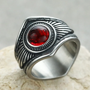 Vista macro de un anillo punk vintage con gema roja y grabados de plumas detallados