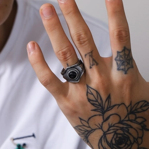 Primer plano de anillo punk vintage de acero con gema negra y patrones radiales