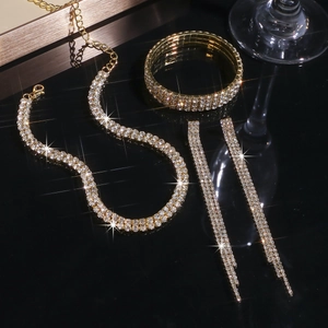 Détail d'une parure de bijoux dorés avec boucles d'oreilles à pompons et bracelet brillant