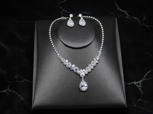 Macro shot of V-shaped rhinestone bridal necklace and teardrop earrings on black stand