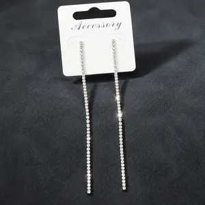 Dettaglio di lunghi orecchini a catena con strass argentati su cartoncino bianco