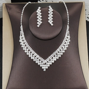Detailed close-up of sparkling rhinestone V-shaped necklace and matching earrings set