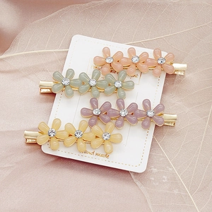 Vue détaillée de quatre barrettes à fleurs colorées avec strass sur carte de présentation
