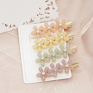 Détail de quatre barrettes à fleurs colorées avec strass brillants sur carte handmade