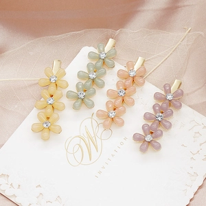 Détail de quatre barrettes à fleurs avec strass sur une base en métal doré