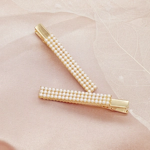 Elegantes Paar Haarspangen aus Goldlegierung mit drei Reihen Perlen auf rosa Seide