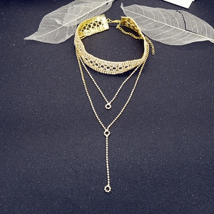 Detalle de gargantilla dorada de varias capas con strass, colgante de borla y banda de encaje