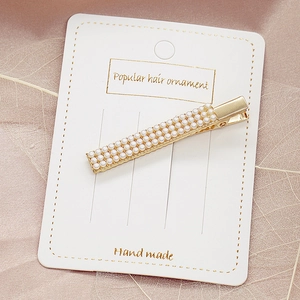 Eleganter goldener Perlen-Haarclip mit drei Reihen weißer Perlen auf rosa Satinstoff