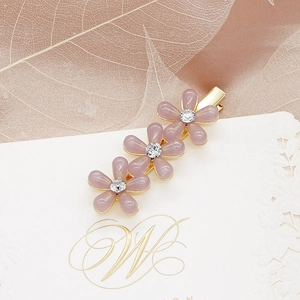 Gros plan sur les pinces à cheveux fleurs mauves avec strass et support doré