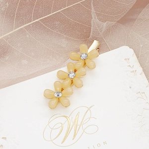 Détail de trois barrettes fleurs jaunes avec strass sur une base en alliage doré