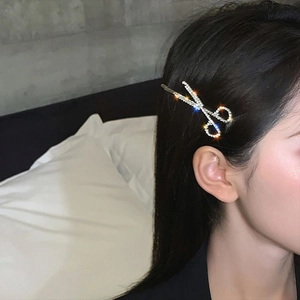 Close-up of creative scissor-shaped hair clip with shimmering rhinestones on a model