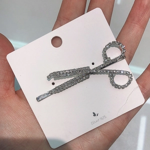 Detailed macro view of a sparkling scissor-shaped hair clip with embedded rhinestones