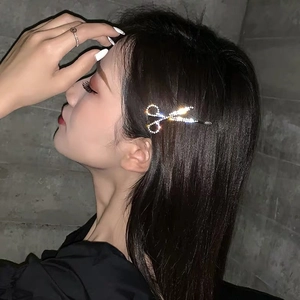 Detail of a sparkling scissor-shaped hair clip with crystals on a woman's hair