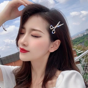 Sparkling silver scissor-shaped hair clip with inlaid rhinestones on female model