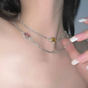 Primer plano de collares tennis en capas con gemas de diamantes rosa y amarillo en acabado plata