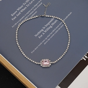 Detalle de una gargantilla plateada con gema rosa rectangular y cristales brillantes
