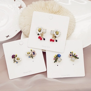 Detail of 925 silver stud earrings set featuring enamel flowers and cherry motifs