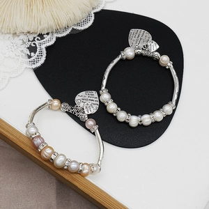 Detail von Süßwasserperlen-Armbändern mit silbernen Herzanhängern und Gravuren