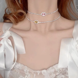 Detalle de gargantillas de pedrería con piedras cuadradas rosas y amarillas en una modelo