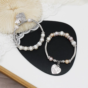 Detail von Süßwasserperlen-Armbändern mit silbernen Herzanhängern und Liebesbotschaften