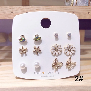 Detail of 6-pair gold plated earring set featuring swan, daisy, pearl, and butterfly motifs