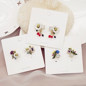Three pairs of floral 925 silver earrings with daisies and cherries on silk background