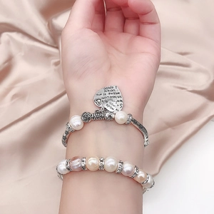 Detail eines Vintage-Silberarmreifs mit Rosenmustern und gestuften Perlenarmbändern