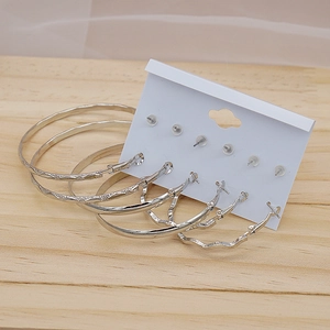 Detailed view of six pairs of assorted silver hoop earrings with various textures on a white card