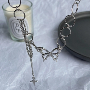 Silver butterfly necklace with chunky chain and fringe star charms on a tray