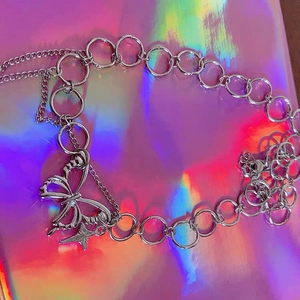 Macro shot of silver butterfly and star charms on a thick industrial chain necklace