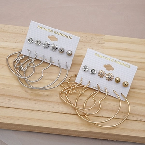 Detailed view of gold and silver earring set featuring daisy studs and heart hoops