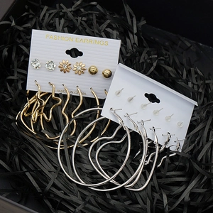 Macro shot of gold and silver hoop earrings and studs set on a black textured background
