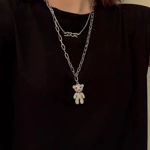 Gros plan du collier double argenté avec un ours en strass et un pendentif SKR