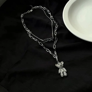 Détail d'un collier double épaisseur argenté avec ours serti et pendentif SKR