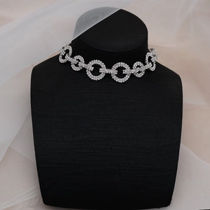 Primer plano de gargantilla de pedrería brillante en maniquí negro con encaje blanco