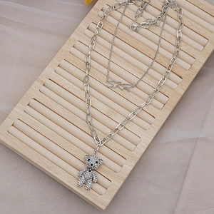Collier double couche argenté avec un ours en strass brillant et un pendentif lettre SKR