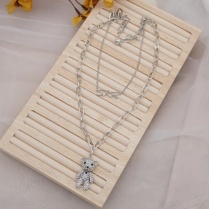 Collier double épaisseur argenté avec pendentif ours et chaîne trombone sur bois