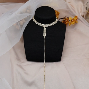 Detailed view of rhinestone tassel choker on a black neck bust with satin background