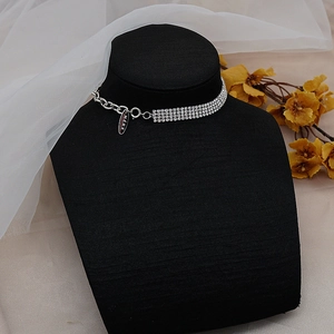 Detalle de gargantilla plateada con filas de strass y eslabones de cadena en soporte negro