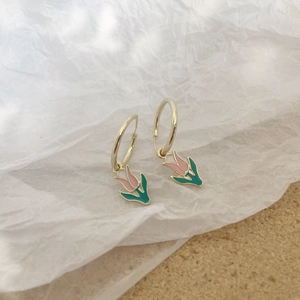 Detalle de pendientes de tulipán dorados con esmalte rosa y aros de metal sencillos