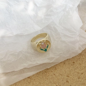 Detalle de anillo de tulipán dorado vintage con esmalte rosa en papel arrugado